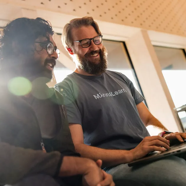 Two colleagues laughing together over a laptop