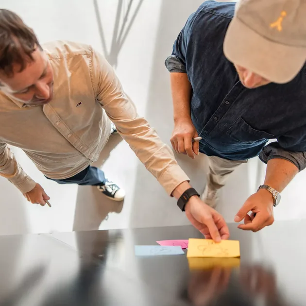 Two colleagues leaning over a table to arrange sticky notes
