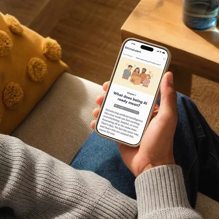 Hand holding a phone that shows a MinnaLearn lesson titled “What does being AI ready mean?”